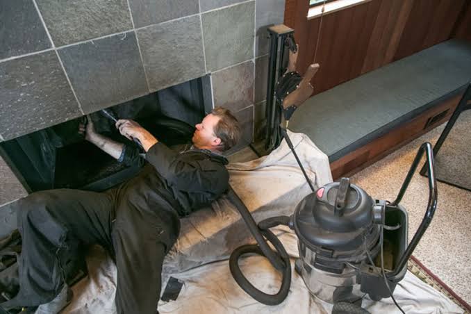 Technician servicing the flue area of a residential fireplace