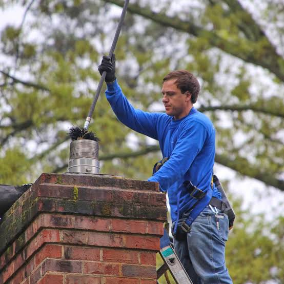 Technician cleaning and checking a metal chimney cap