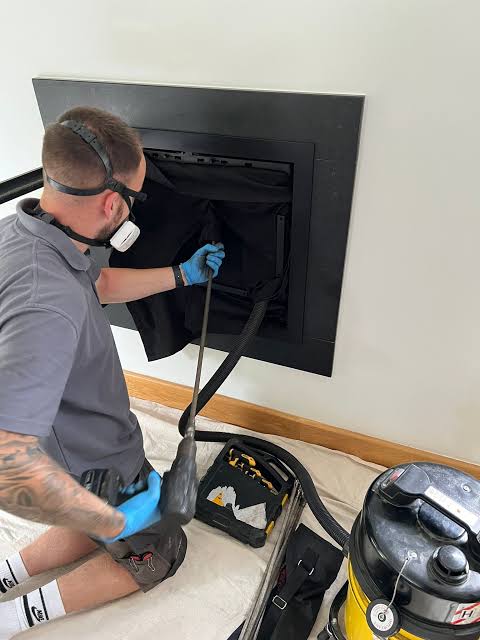 Technician cleaning a residential fireplace with professional vacuum equipment