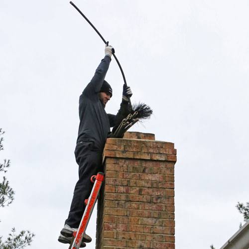Technician servicing the top of a residential brick chimney