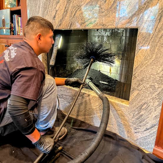 Chimney technician sweeping a residential fireplace and flue