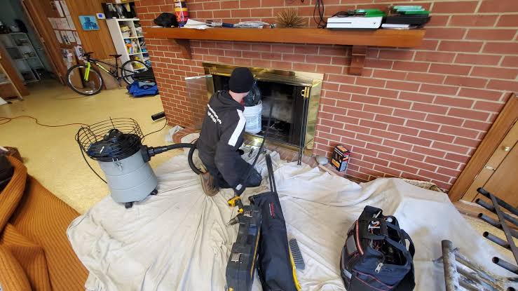 Technician servicing a fireplace with professional vacuum equipment